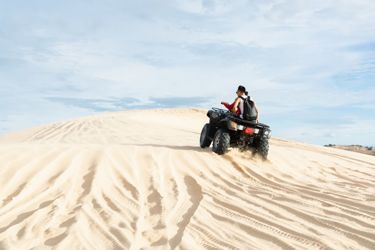 Dune buggy speeding through the sand dunes of Mui Ne with two passengers inside